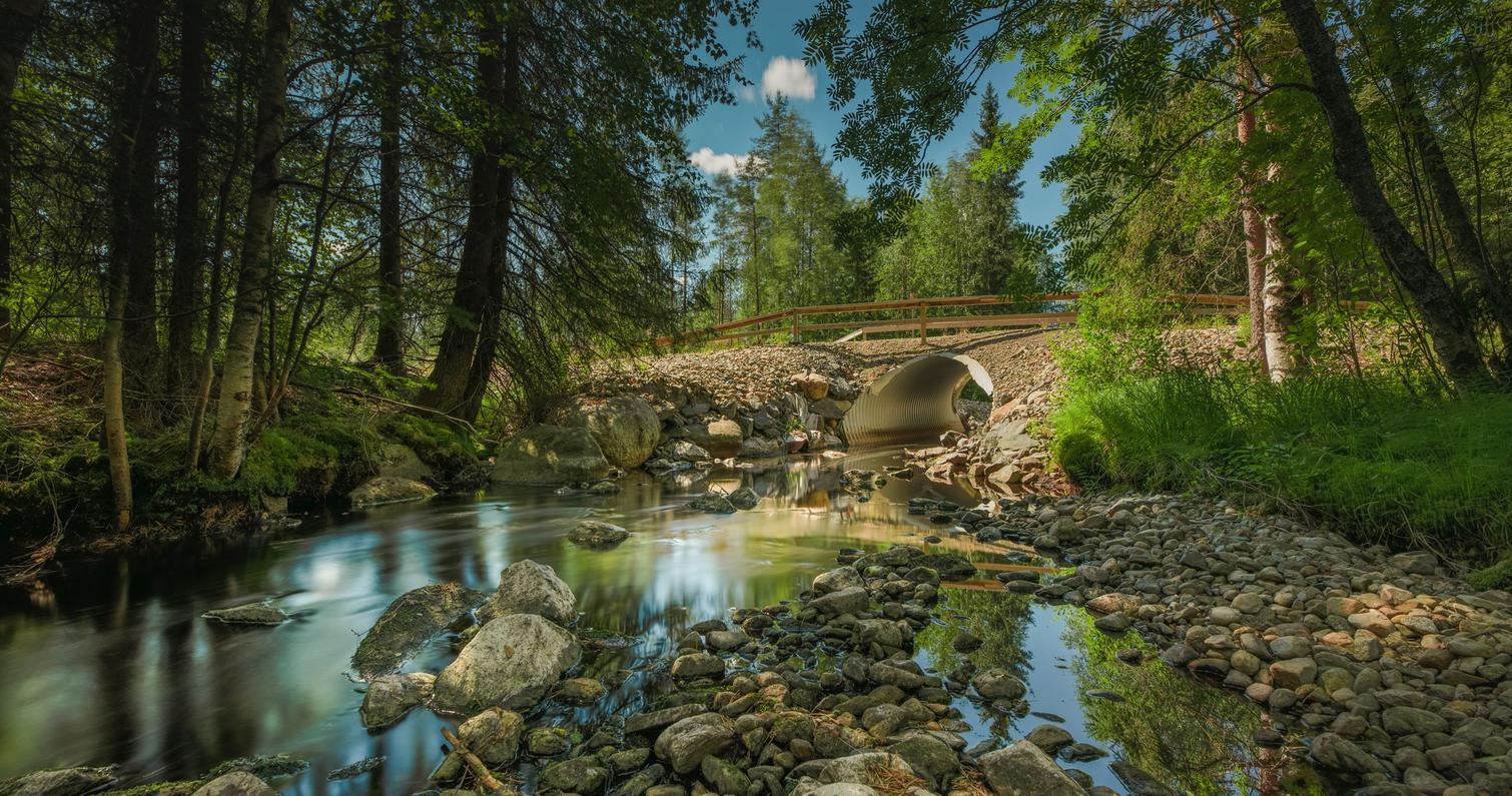 Suojoki bridge in the background, flowing water in the foreground